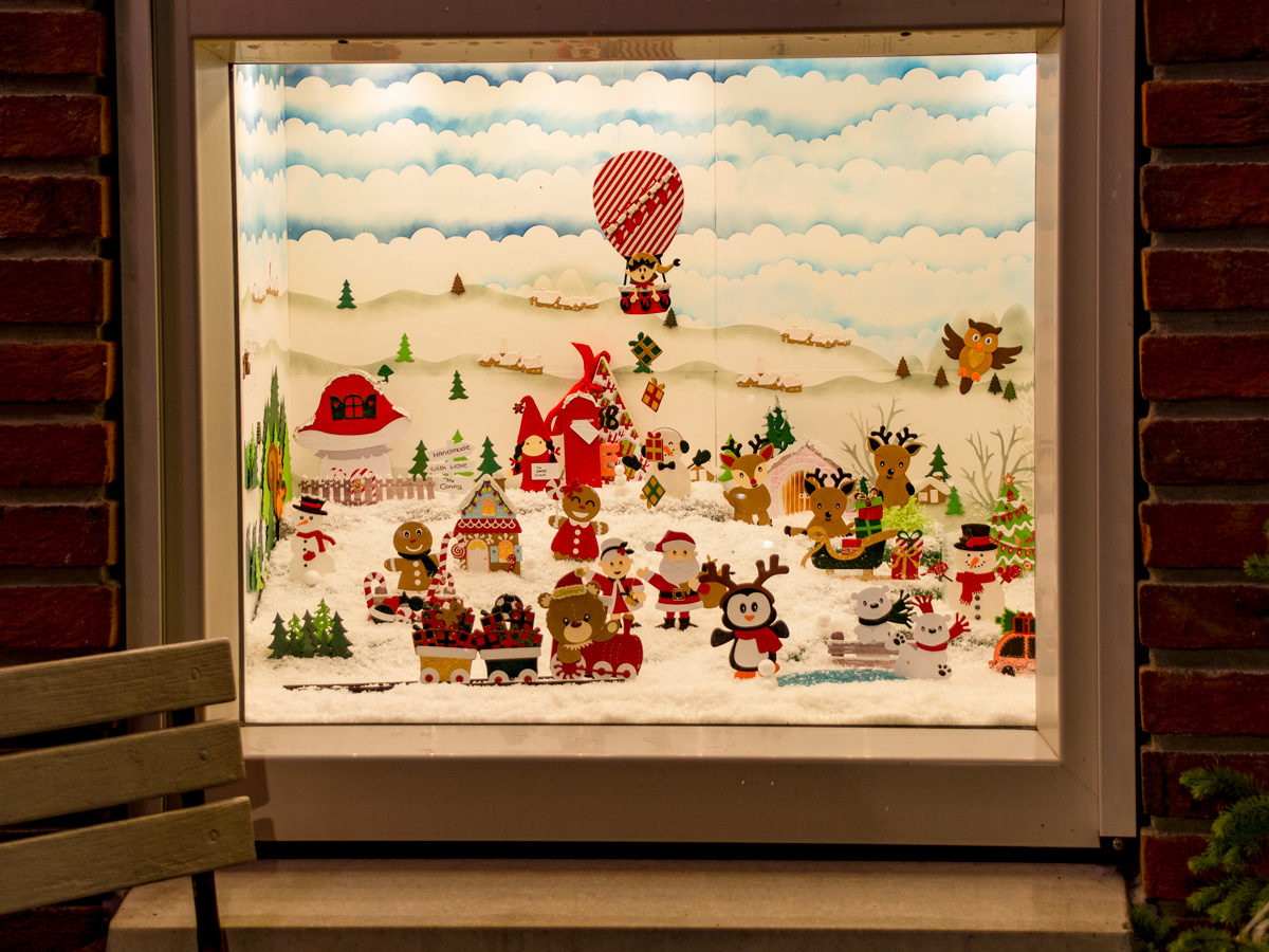 Een raam met een uitgestald landschap met uitgeknipte kerstfiguurtjes